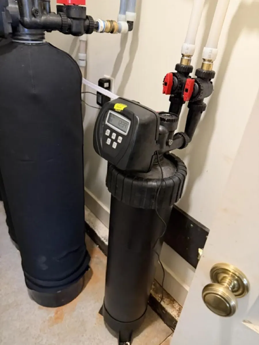 Water softener with a digital control valve installed beside a filtration tank