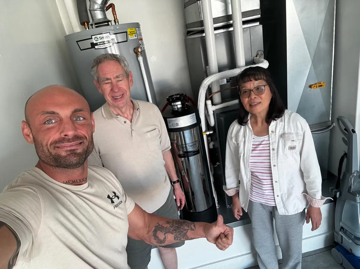 Smart Living Water technician with a homeowner couple beside their new whole-home water system