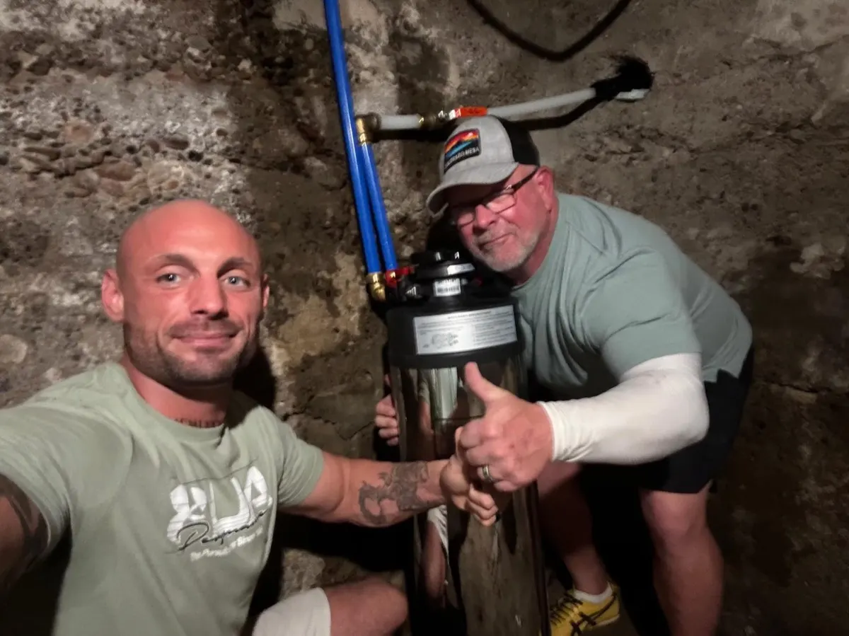 Homeowner and technician with a stainless system installed in a stone-walled basement
