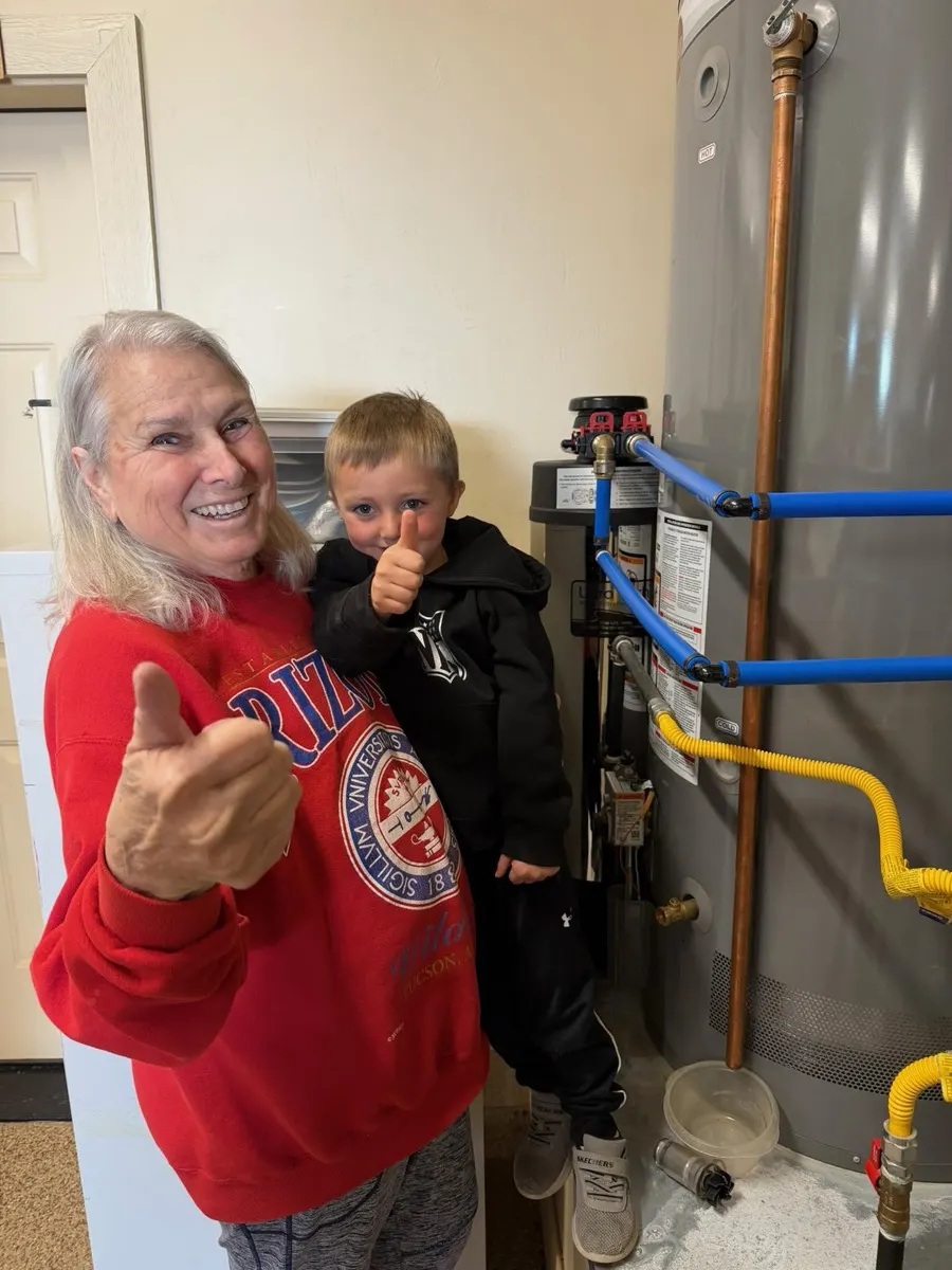 Homeowner and grandson giving a thumbs-up next to their new water treatment system